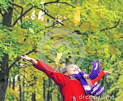 Little laughing pretty girl in red coat throws yellow leaves in autumn park Stock Photo