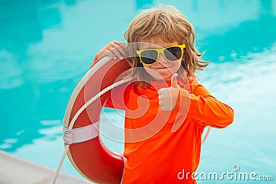 Little lifeguard show thumb up, ok. Summer kids holidays. Happy child playing with lifebuoy in the sea. Kids having fun Stock Photo