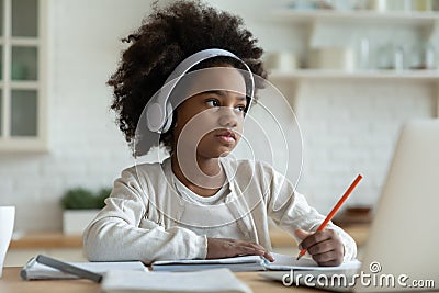 Little mixed race kid girl in headphones feeling tired. Stock Photo