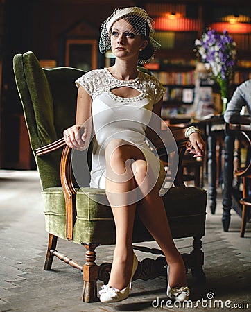 Little mysterious lady in a hat sits straight in a big chair Stock Photo