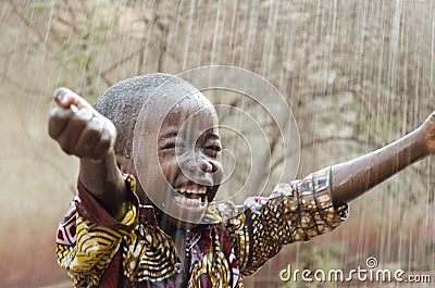 Little Native African Black Boy Standing Outdoors Under the Rain Water for Africa Symbol Stock Photo