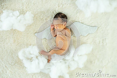 Little newborn baby is sleeping on white bed with wing accessory and fluffy pandas Stock Photo