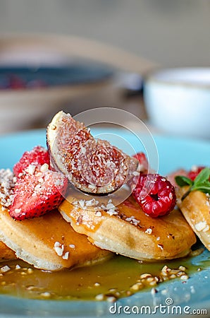 Little pancakes with fruits strawberry, fig, raspberry with caramel souce on plate in restaurant. Breakfast Stock Photo