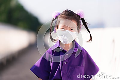 Little preschool student with a new normal lifestyle. Girl wearing white cloth mask was walking to school in the morning. Stock Photo