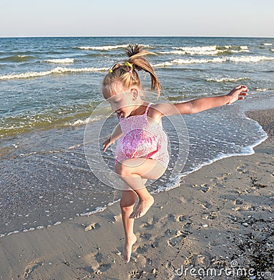 Little pretty girl on summer beach. Cheerful little girl dancing on the background of blue sky and summer sea Stock Photo