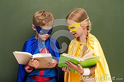 Pupils in superhero costumes with books Stock Photo