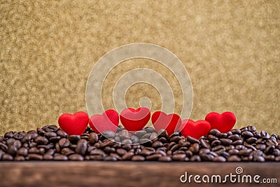 Little red satin hearts with letters on coffee beans with gold background, valentines day or wedding day celebrating Stock Photo