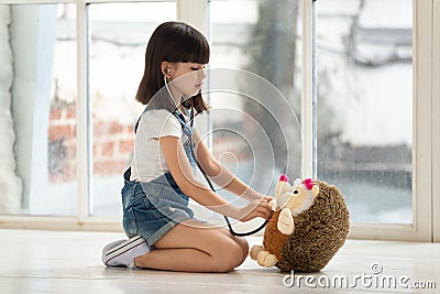 Little school girl playing with toy, pretending to be doctor. Stock Photo