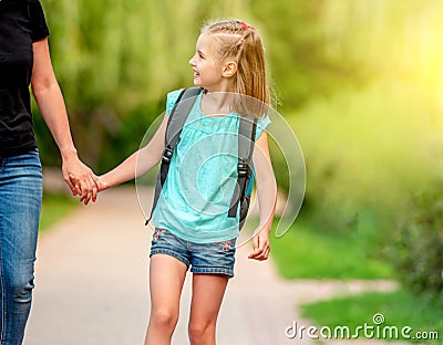 Little schooler walking with mother in park Stock Photo