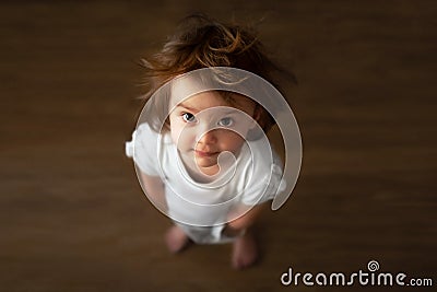 A little shaggy girl with big eyes stands and looks up. top view close up Stock Photo