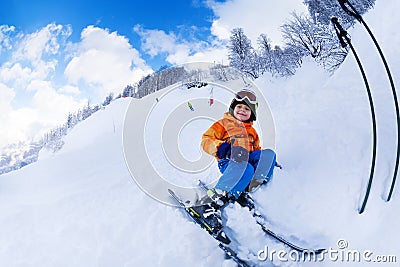 Little skier boy sit with ski in snow resting Stock Photo