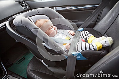 Little sleeping three month old baby child fastened with security belt in safety car seat Stock Photo