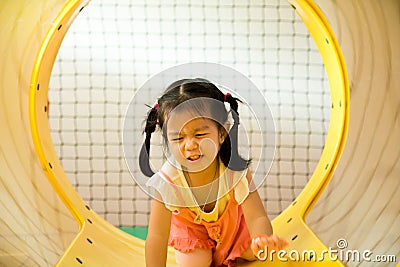 A little smile girl is crawling out of yellow tunnel at playground Stock Photo