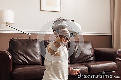 Little smiling boy wearing VR goggles using a controller for interaction in a game Stock Photo