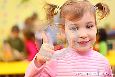 Little smiling girl in kindergarten shows ok Stock Photo