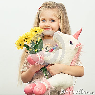 Little smiling girl with white unicorn toy. Stock Photo