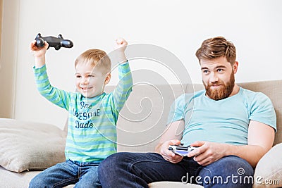 Little son playing computer games with father and winning Stock Photo