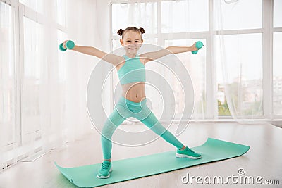 Little sporty girl gymnast in sportswear doing exercises on a mat indoor Stock Photo