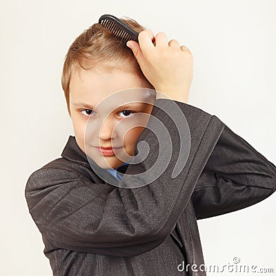 Little stylish boy in a business suit brushing his hair hairbrush Stock Photo