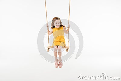 Little stylish child in dress riding on swing Stock Photo