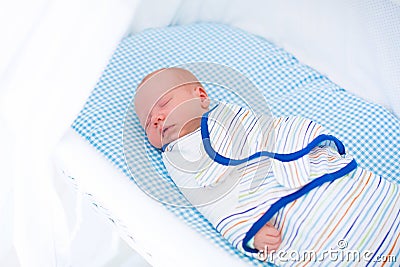 Little swaddled baby in white bed Stock Photo