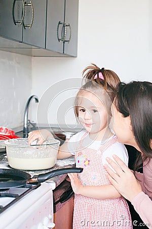 Little sweet girl and her mother fry pancakes at the traditional Russian holiday Carnival Maslenitsa Shrovetide Stock Photo