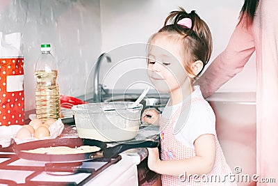 Little sweet girl and her mother fry pancakes at the traditional Russian holiday Carnival Maslenitsa Shrovetide Stock Photo