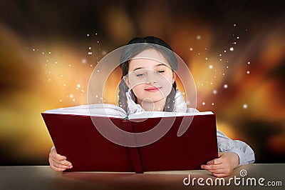 Little teen girl reads magical fairy tutorial book smiling Stock Photo