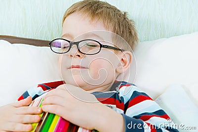 Little tired boy sleeping with book in bed Stock Photo