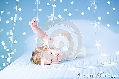 Little toddler girl in bed between sparkling blue lights Stock Photo