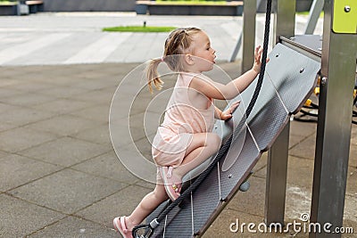 Little toddler girl having fun at playground. Educational playground equipment. Sensory experience Stock Photo