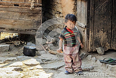 Little toddler Nepalese child boy playing in the yard at the door of a village house in the Himalayas of Nepal Editorial Stock Photo