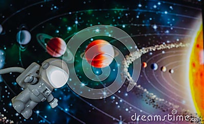 Little toy astronaut traveling through space, with a background of the planets of the solar system. Stock Photo