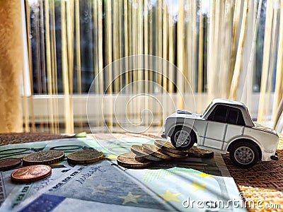 Little toy white car and euro money. Concept of the expensiveness of buying a new car, affordability of buying an old Stock Photo