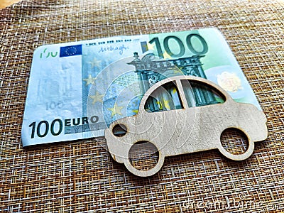 Little toy wooden car and euro money. Concept of the expensiveness of buying a new car, affordability of buying an old Stock Photo