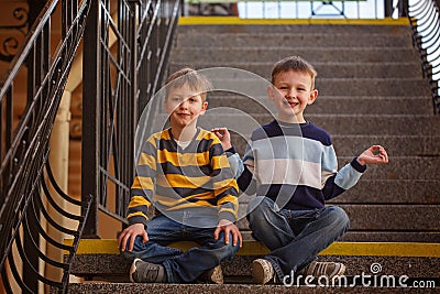 Little two boys sitting on stairway in sunny day. Stock Photo