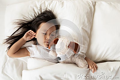 Small Asian girl sleep in bed with fluffy toy Stock Photo