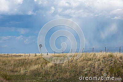 Little Windmill in a golden wheat fied against a blue sky with clouds Stock Photo