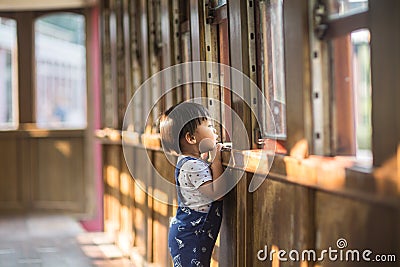 A lively little boy in blue overalls plays in a train car Stock Photo