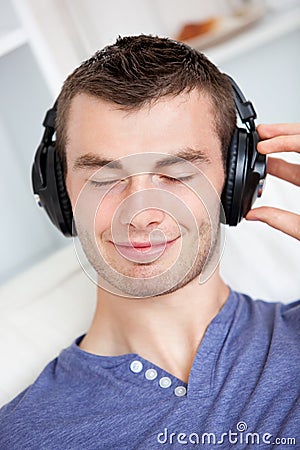 Lively young man listening to music on the couch Stock Photo