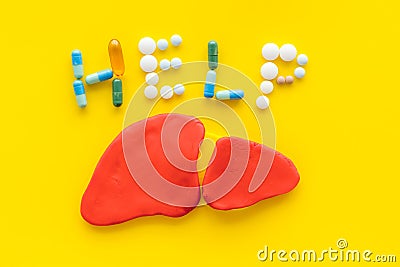 Liver diseases and treatment. Word help and organ on yellow background top view Stock Photo