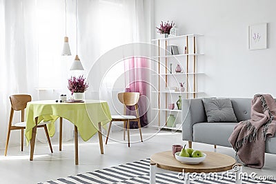 Living and dining room in apartment with grey couch and wooden furniture, real photo Stock Photo