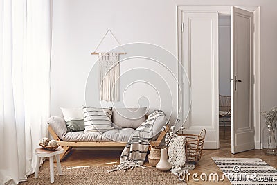 Living room with stylish macrame, sofa, wooden accessories and doors open to next room Stock Photo