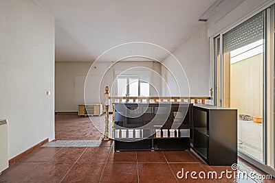 Living room on two levels of a house with aluminum and glass windows, a lot of dust on the floor and an empty porch Stock Photo