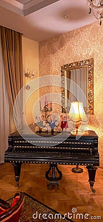 Living room, the warmth of home, an elegant concert piano with three teddy bears, golden mirror, chandelier and painted walls Stock Photo