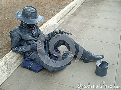 A living statue of an Italian ganster sitting, asking for handout and keeping revolvers Editorial Stock Photo