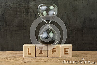 Living time for human life countdown, lifetime or retirement concept, sandglass or hourglass on wooden cube block with alphabet Stock Photo