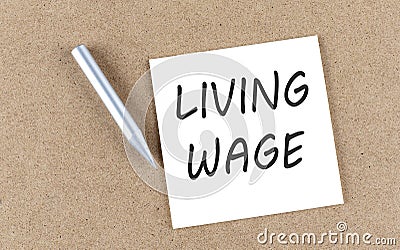 LIVING WAGE text on a sticky note on cork board with pencil Stock Photo