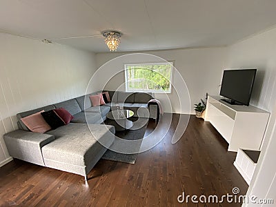 Livingroom with big grey sofa and flatscreen TV white walls Stock Photo