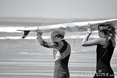 Surfers walking towards the water`s edge at Llangennith Beach on the Gower Peninsula Editorial Stock Photo